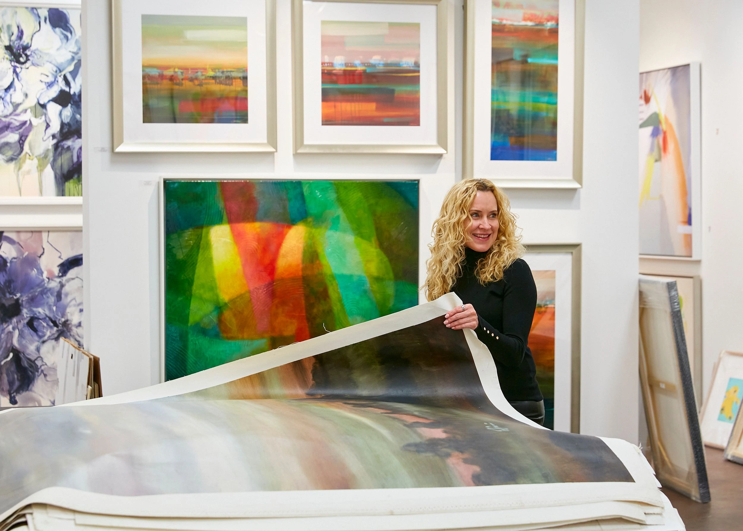 DAC Art Consulting president Cheryl Heisterberg holding artwork representing hospitality art collaboration and creative leadership