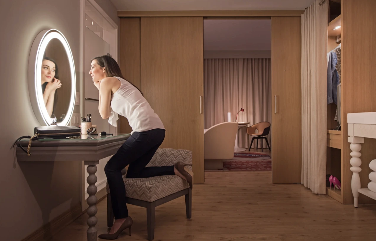 hotel guest using illuminated makeup mirror designed to support comfort, functionality, and the hospitality experience