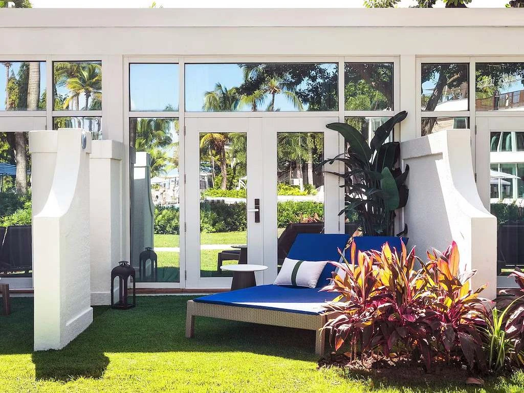 Outdoor lounge chair on a lawn beside glass doors, with tropical landscaping at Fairmont El San Juan Hotel.