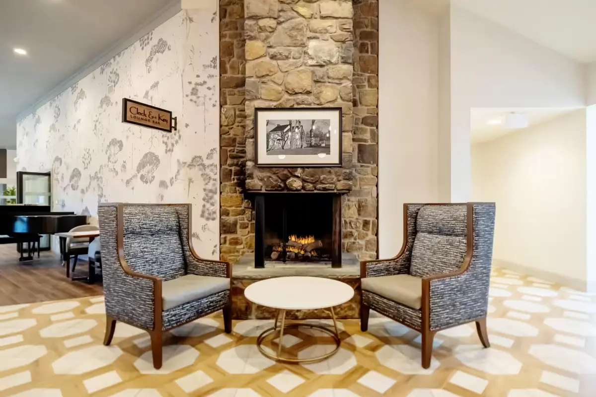 Fireplace seating area at Bellingham at West Chester with two patterned upholstered armchairs and a round accent table.